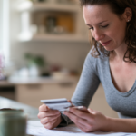 amerihealth-therapist-princeton-nj - Caring Clarity Counseling Woman in a Gray Long-sleeve Top Sits at a Kitchen Table, Reviewing Several Cards in Her Hands.