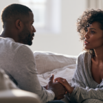 a Man and a Woman Sit on a Sofa, Holding Hands and Talking Warmly in a Bright Living Room.